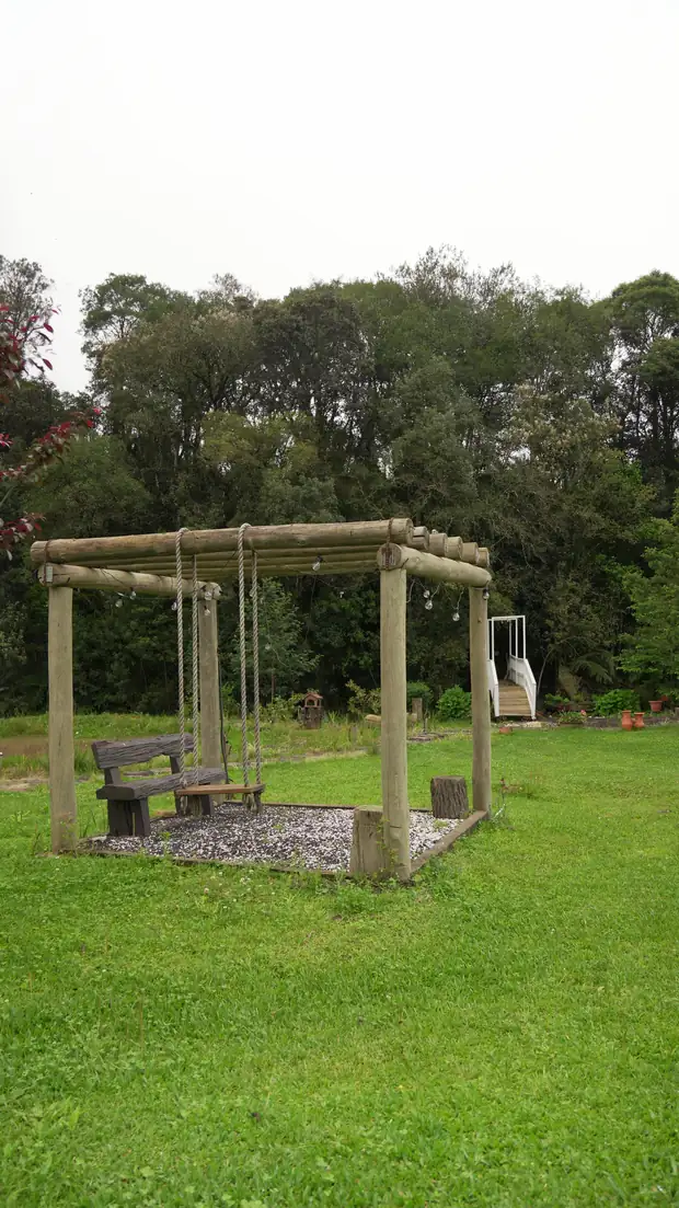 Pergolado de madeira com balanço no gramado