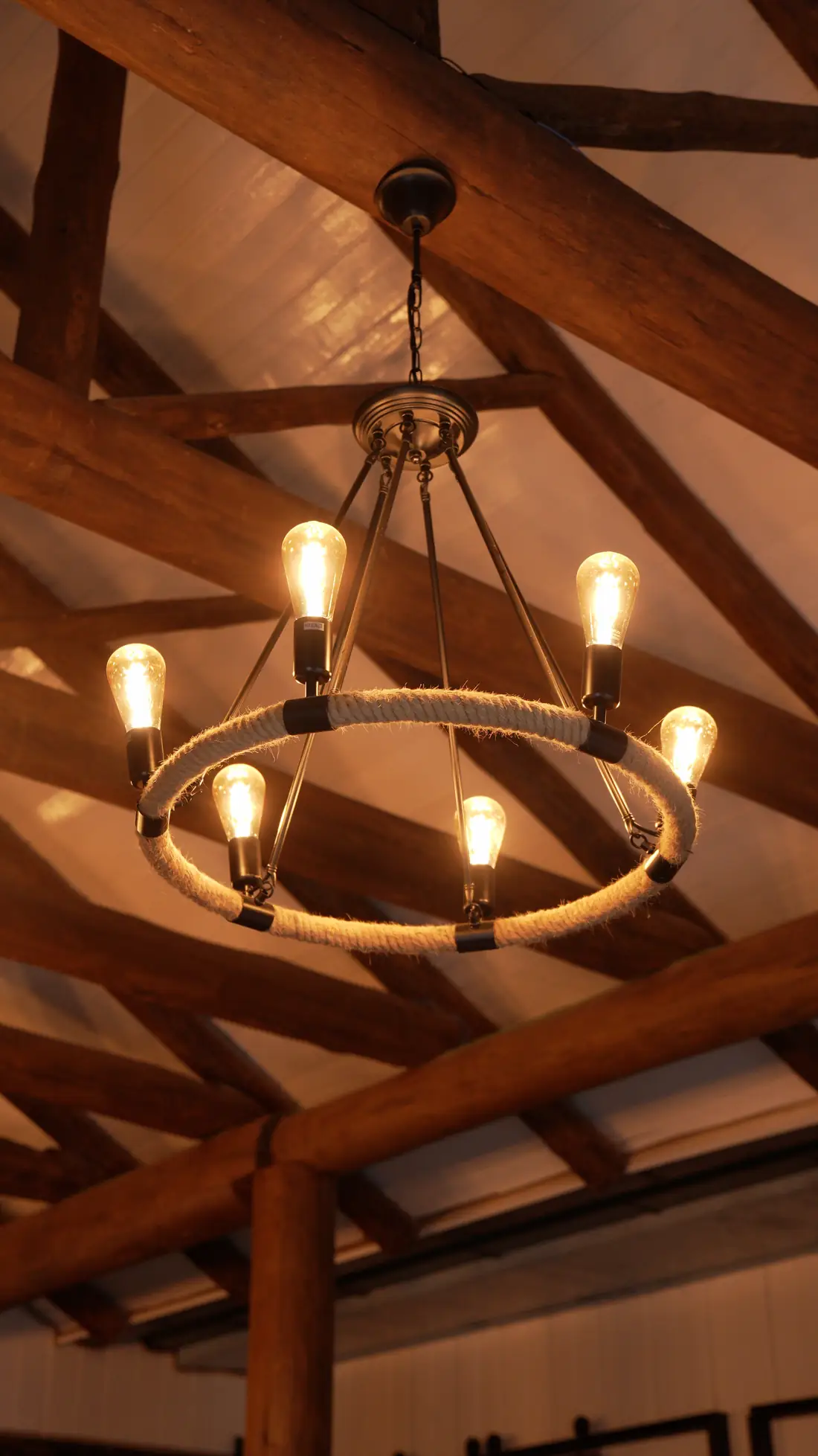 Lustre de ferro com lâmpadas acesas sob o telhado de madeira
